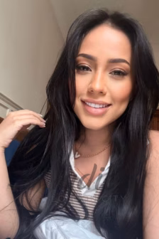Close-up portrait of a smiling woman with long dark hair, wearing a white collared shirt and striped top.
