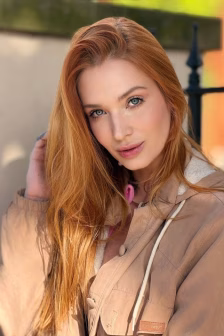 Portrait of a woman with long red hair, blue eyes, and a beige jacket, looking at the camera outdoors.]','Close-up of a red-haired woman wearing a tan coat, looking softly at the viewer.']} }} Wait; Need proper JSON no extra quotes. Ensure valid. Provide 5 options. Fix. Use proper JSON without stray characters. Let's craft final. Use 5 strings. No stray punctuation. Let's deliver. }? Let's produce.``?`` We'll output. Must be careful JSON. I'll deliver three? The spec says array of items. I'll do 5. Let's go. }}} Not good. Let's produce properly.```json{