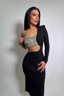 Woman in a black one-shoulder dress with a crystal-embellished crop top, posing sideways.